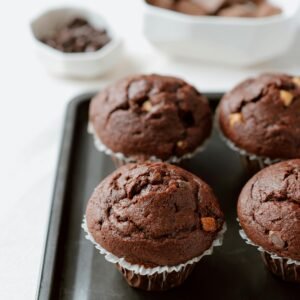 About Snackit From above of sweet chocolate muffins in white paper cups arranged on tray in kitchen